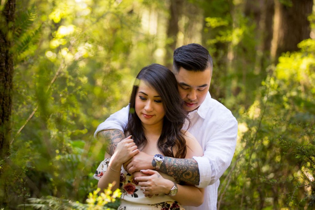 image of groom with his arms around this bride during a boho engagement session in the redwood forest