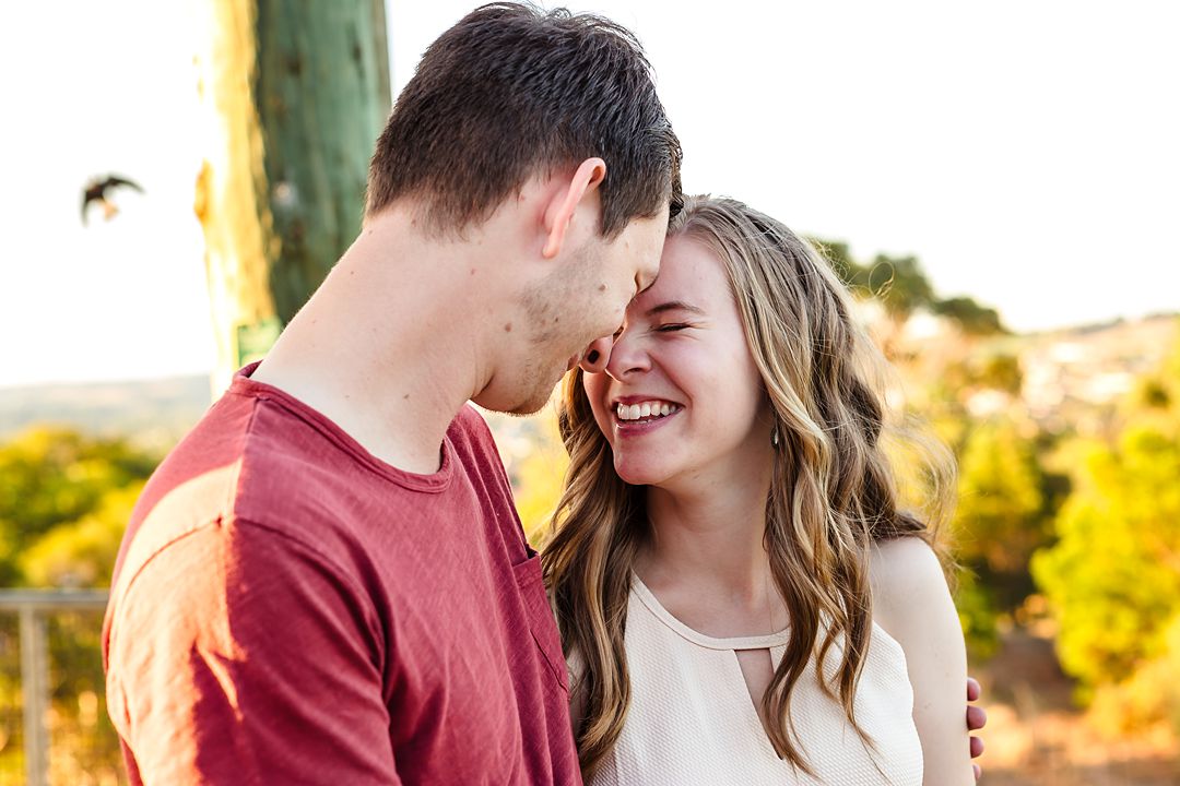 engaged couple touching heads and smiling during engagement photo session at wilson botanic park