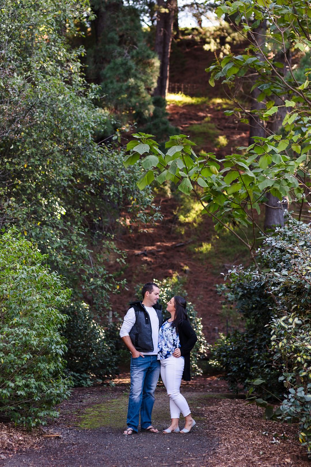 couple holding each other and the wilson botanic park with trees all around them