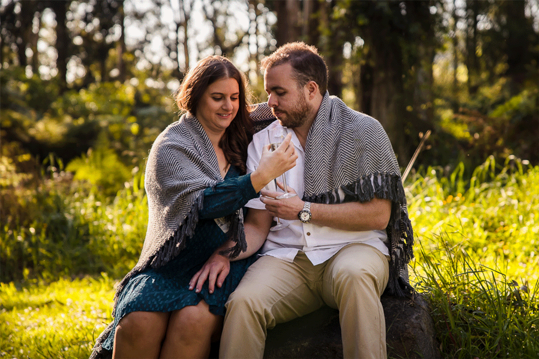 melbourne couple sitting on a rock drinking champagne under a blanket during couple photography session