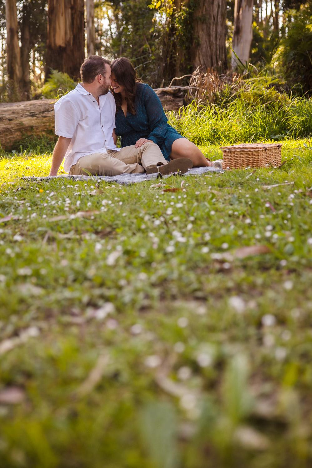couple sitting on a picnic blanket and kissing