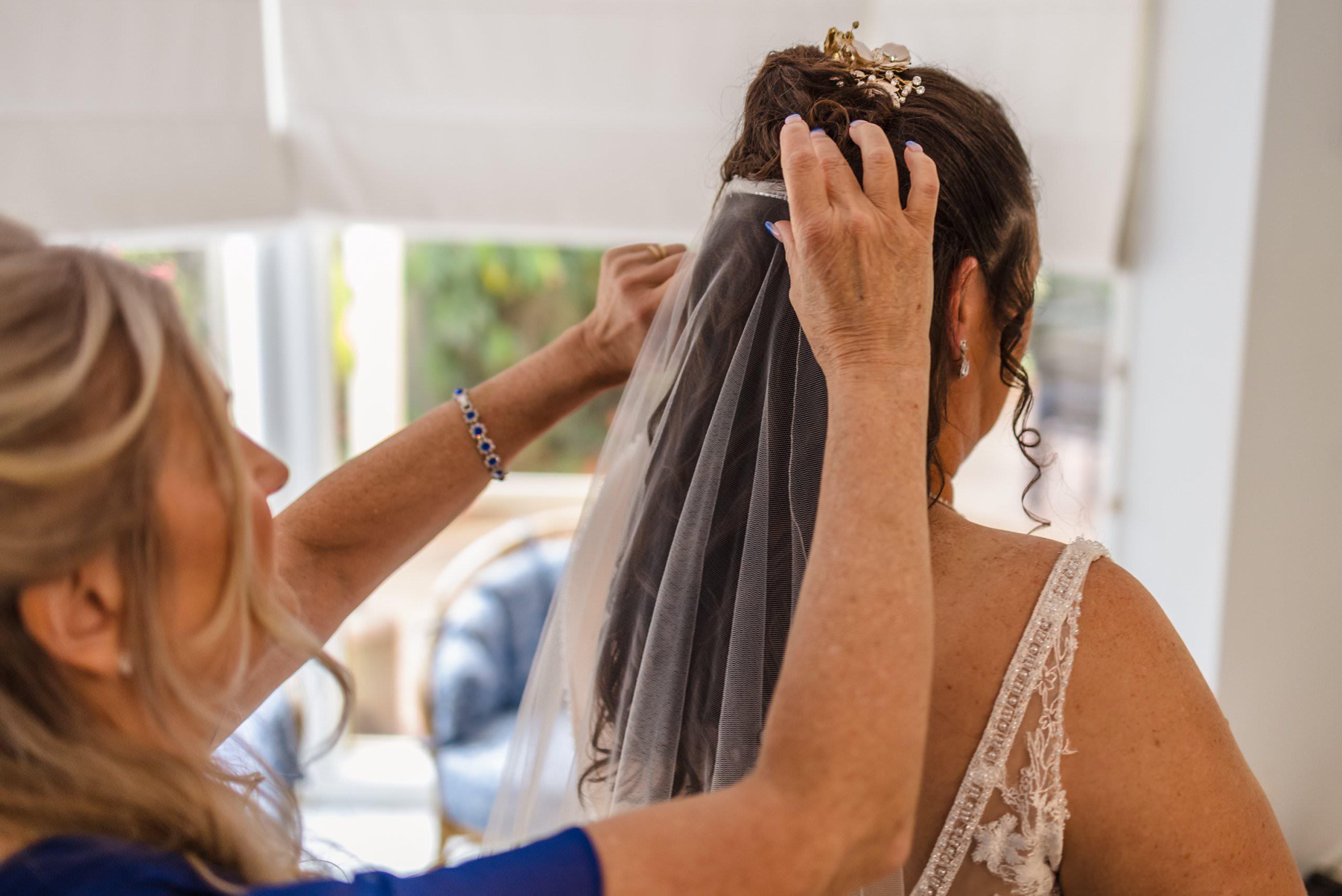 brides best friend putting veil on the bride