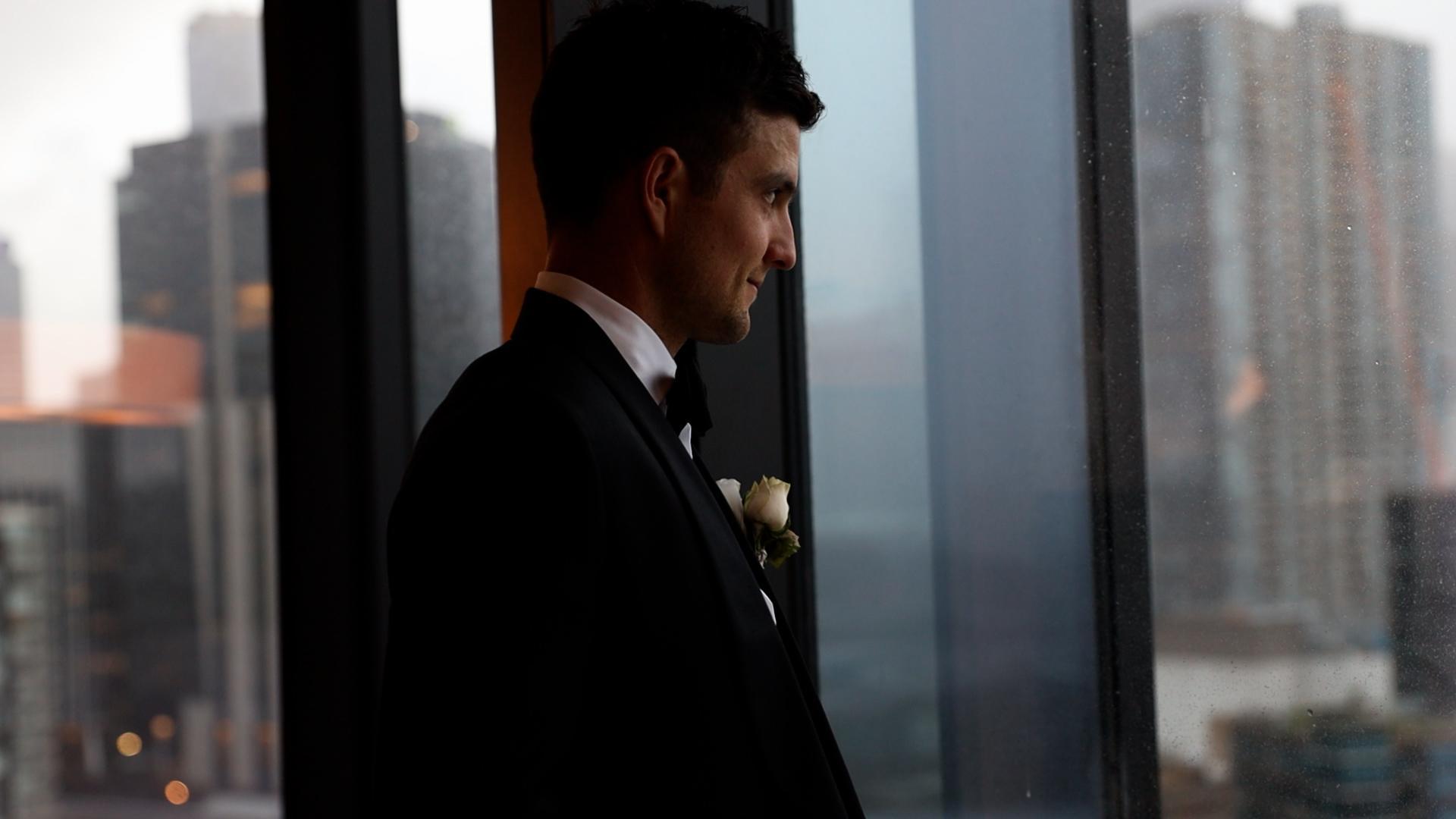 groom looking out the window waiting for the first look with his bride