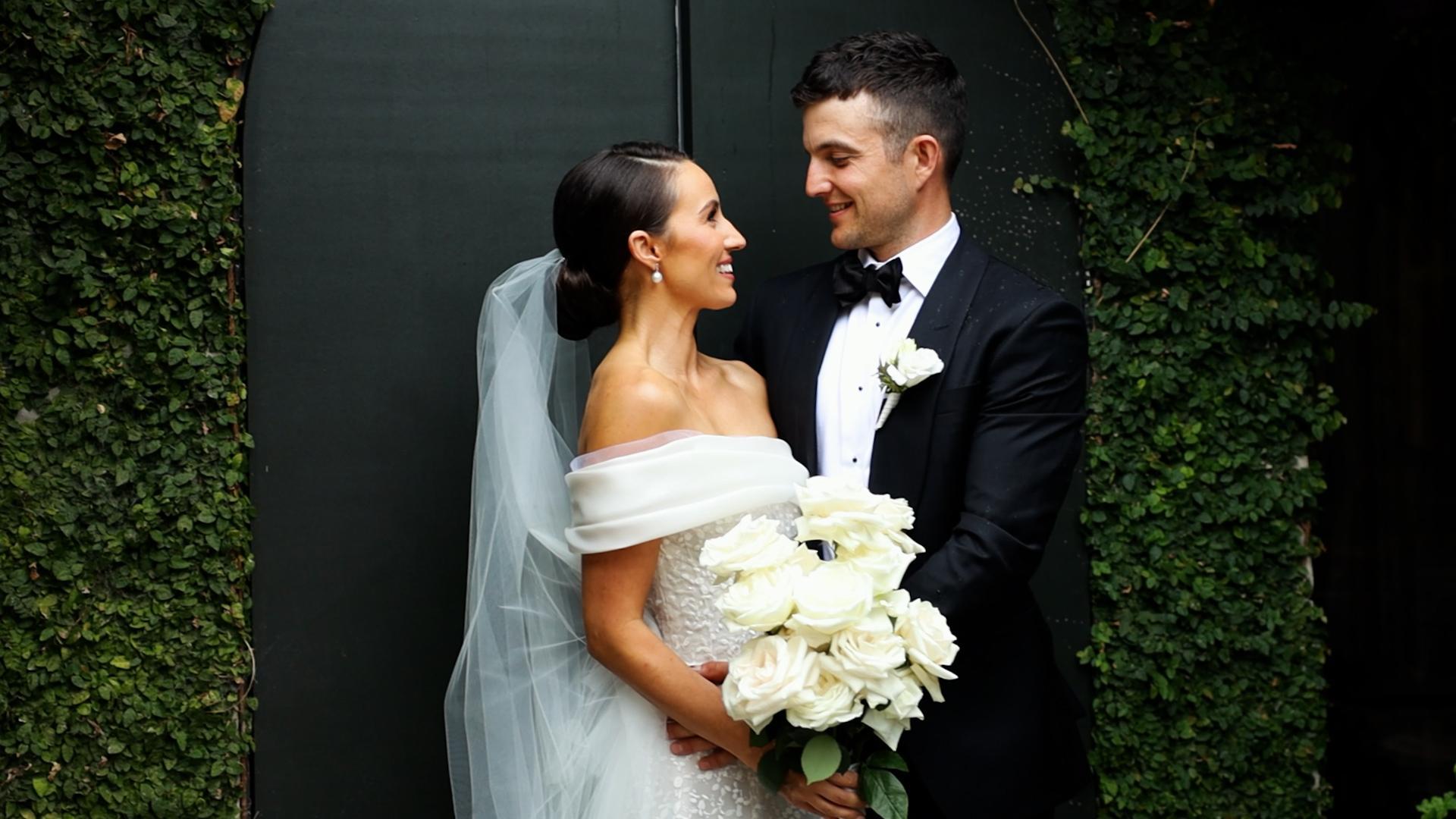 portrait of newlyweds at the door of half acre with green vines 