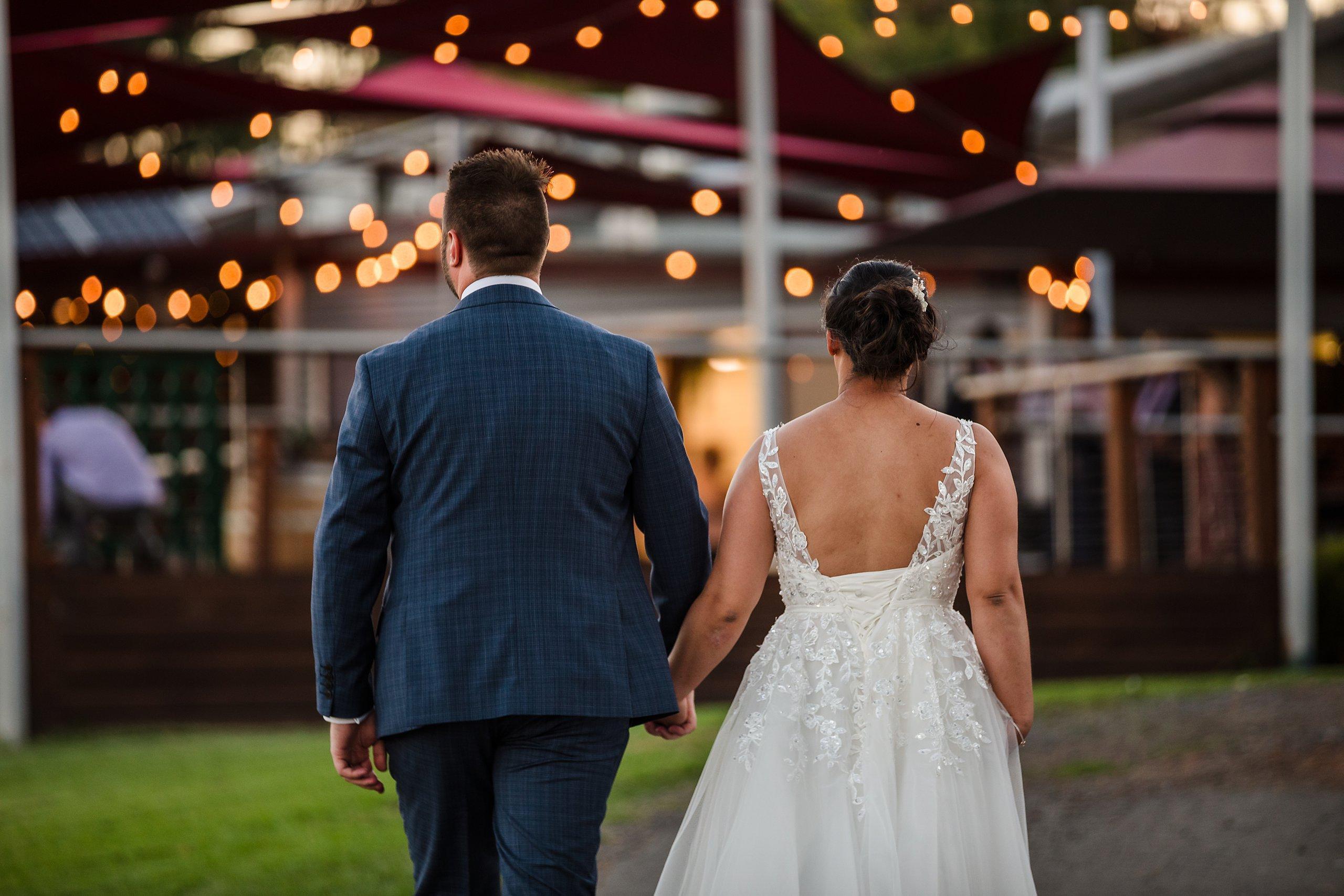 couple walking back into venue on their wedding day with the fairy lights in the distance