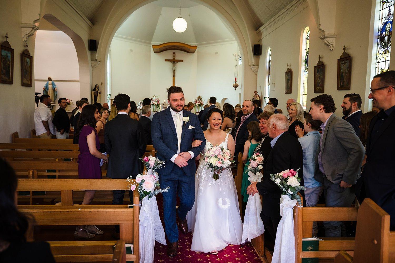 married couple walk through the church hand in hand