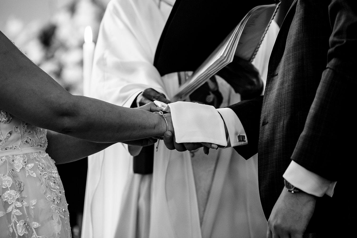 priest covers couples hands with rope during church ceremony