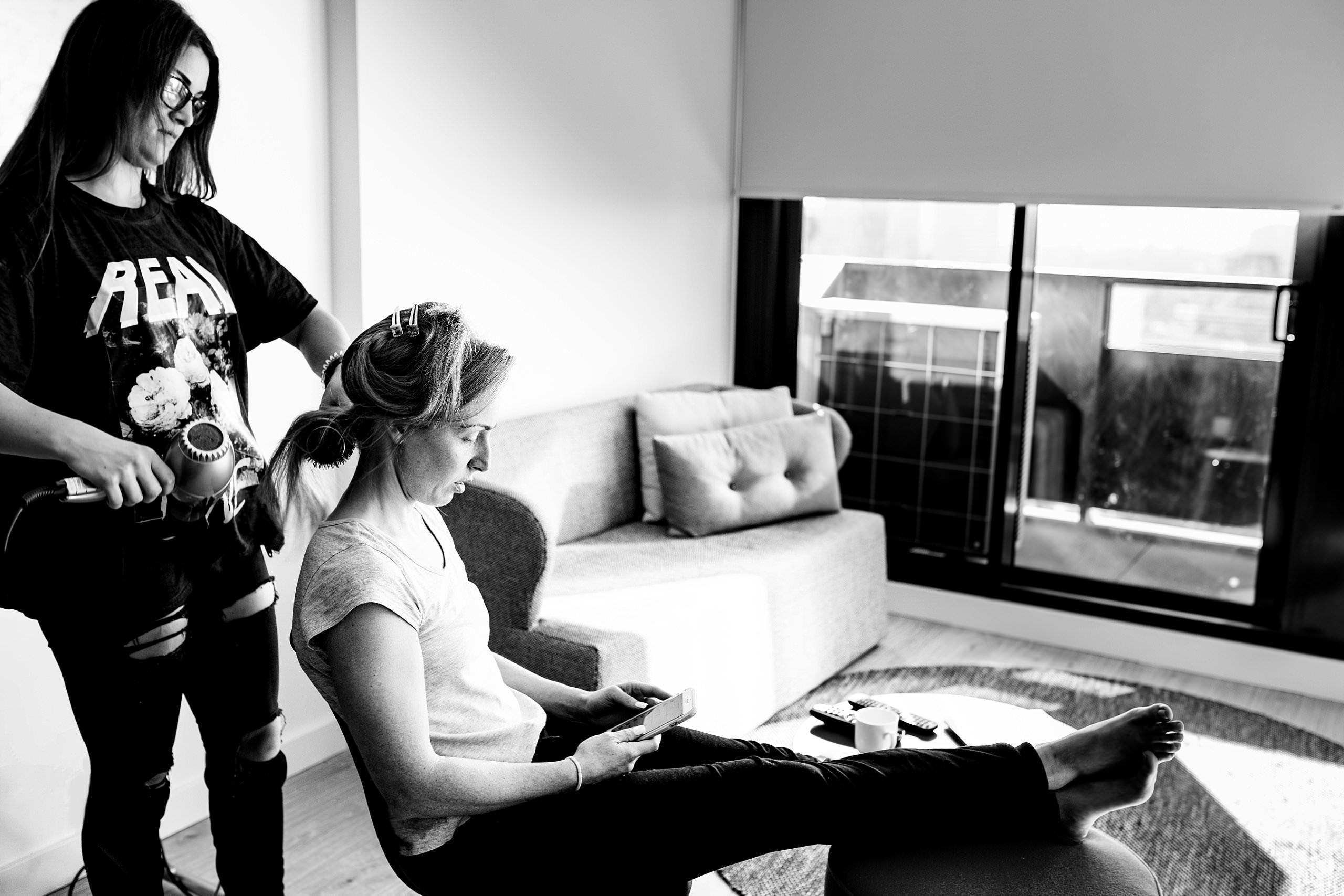 black and white image of bride having her hair done in hotel before her wedding two ton max begins