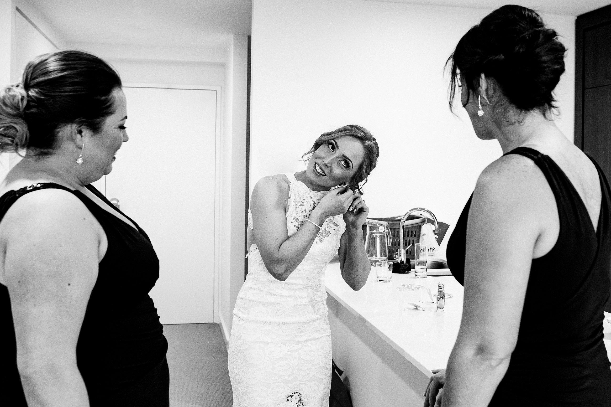 bride putting on earring before the wedding ceremony