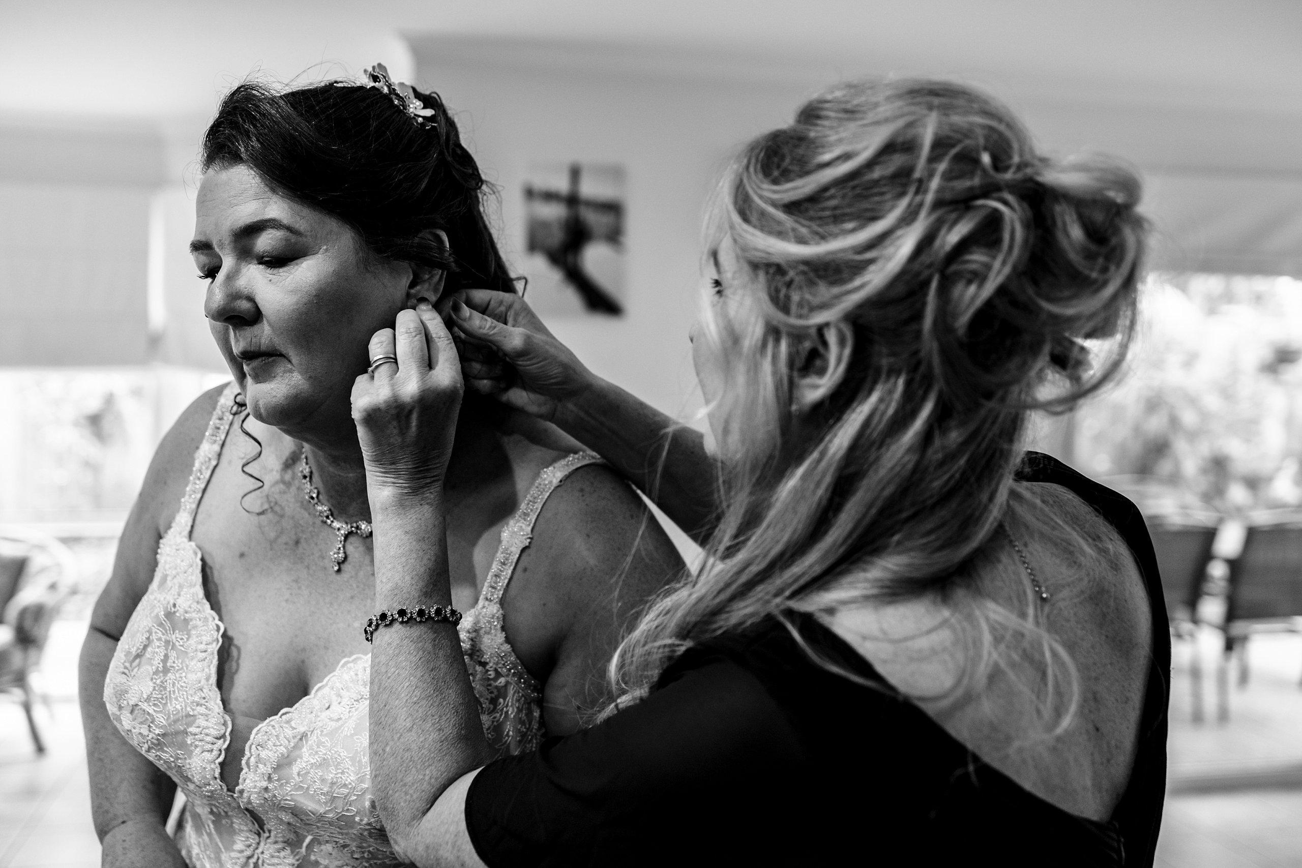 old cheese factory wedding bridesmaid helps bride put on earrings on