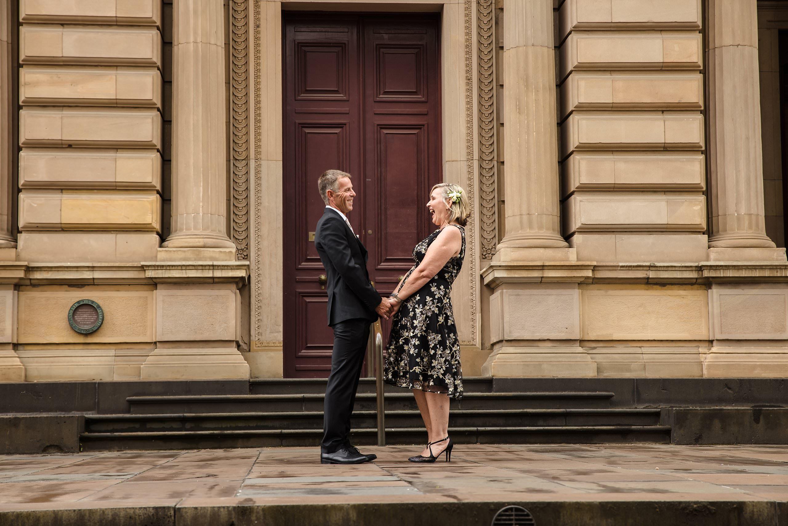 old treasury building wedding couple holding hands in front of the building