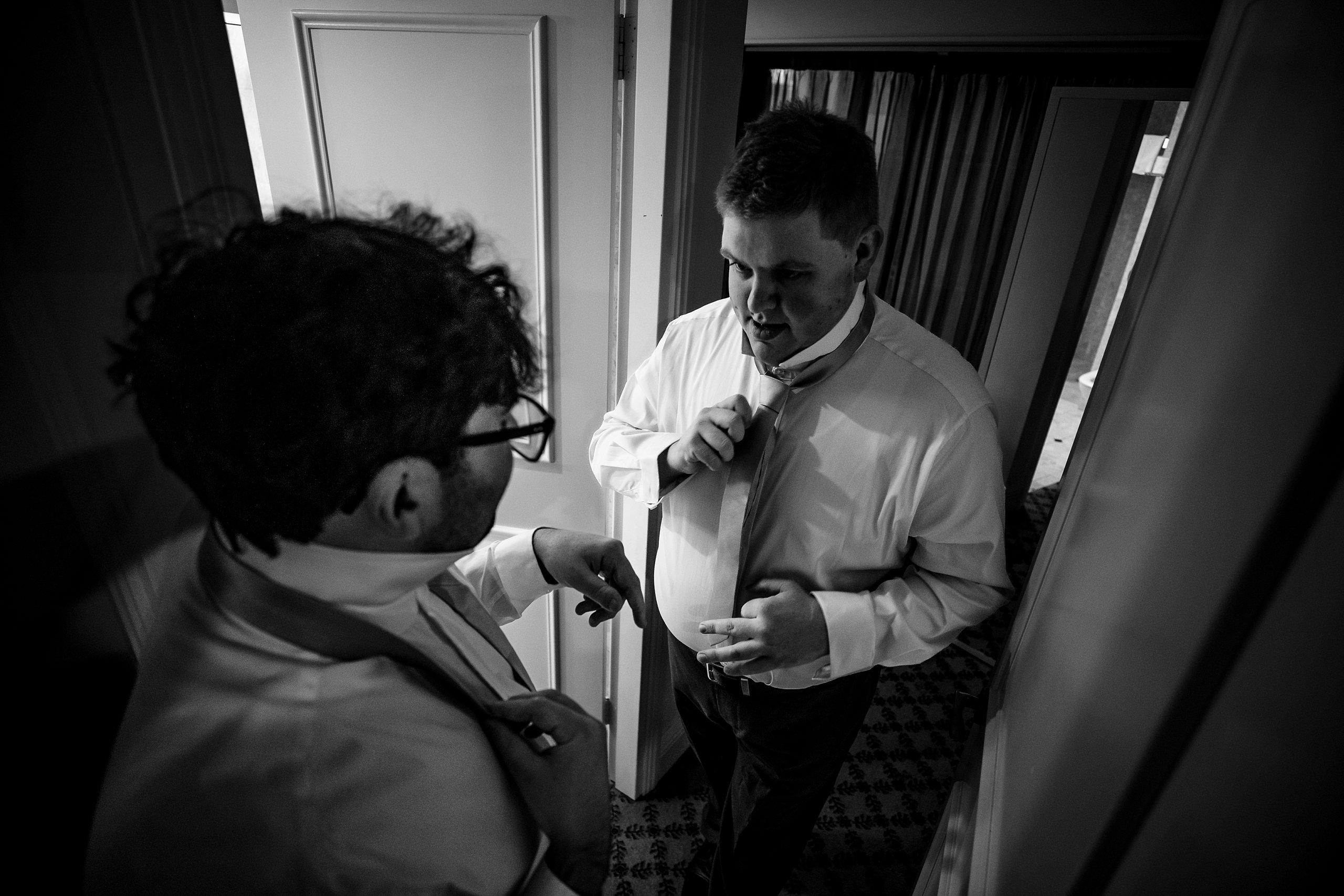 groom with is bestman putting on a pink tie
