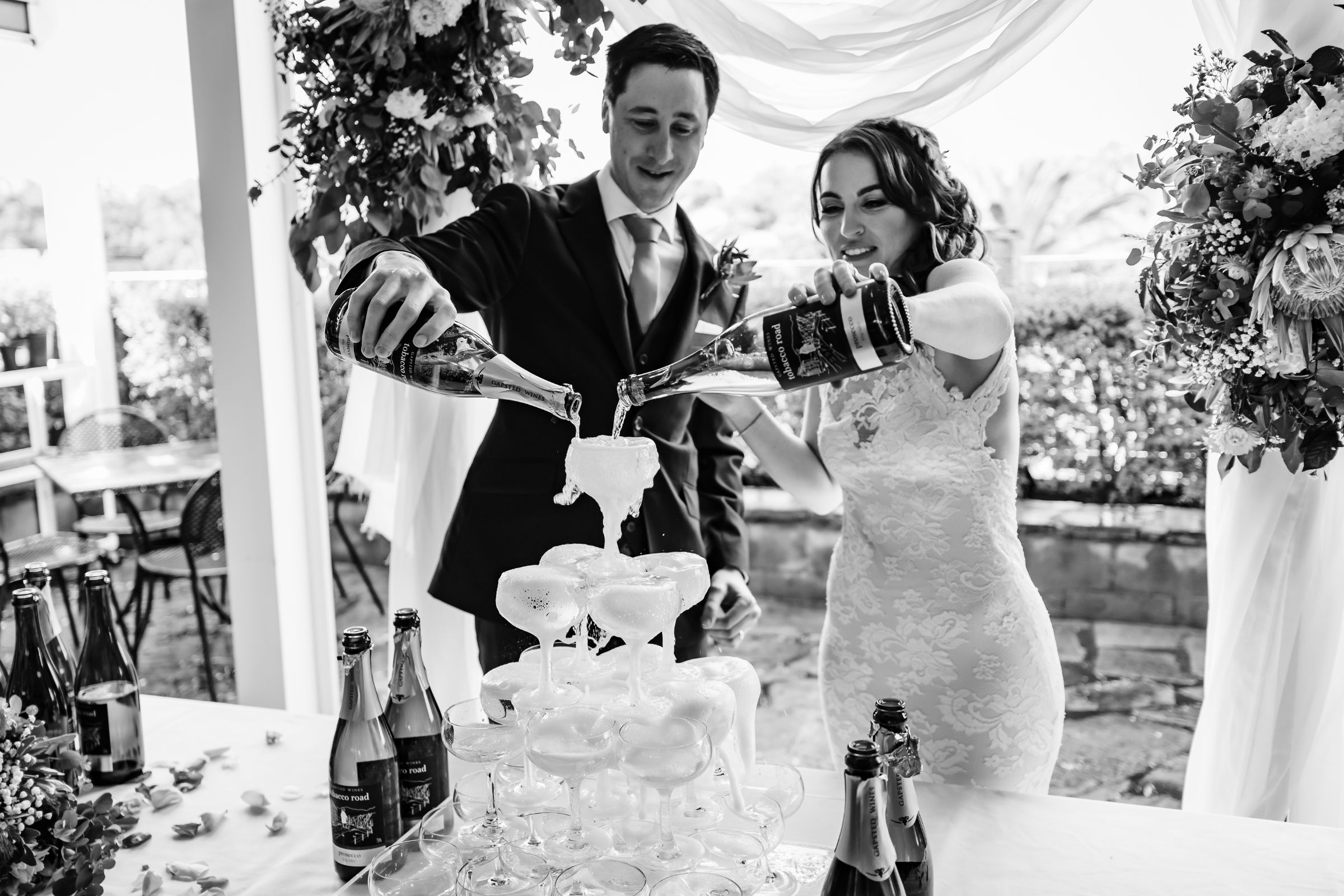 bride and groom pouring champagne into glasses