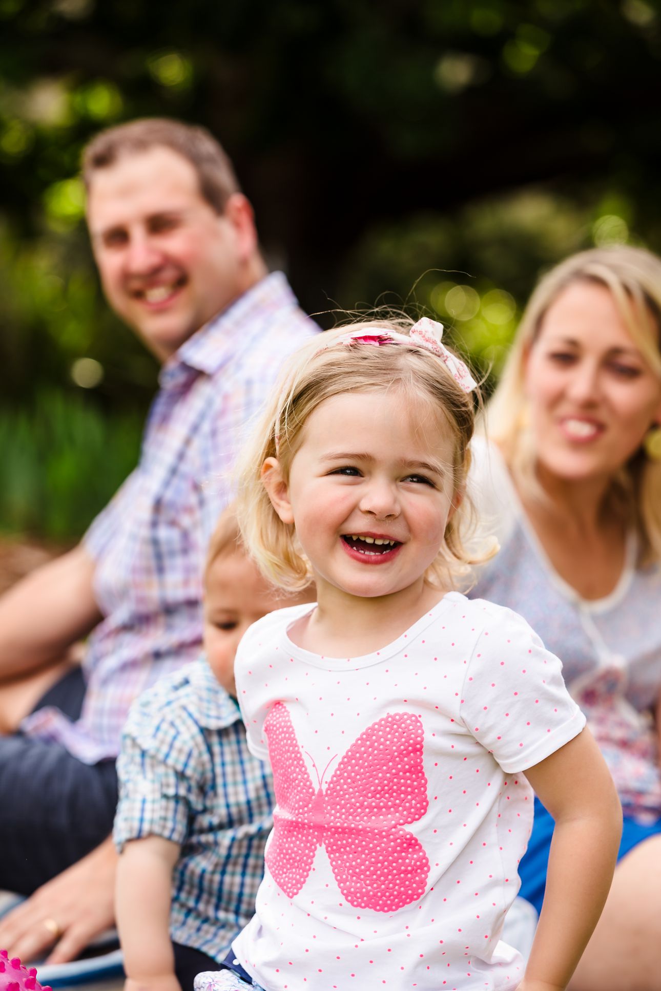 little girl smiling with her family behind her during family photo session