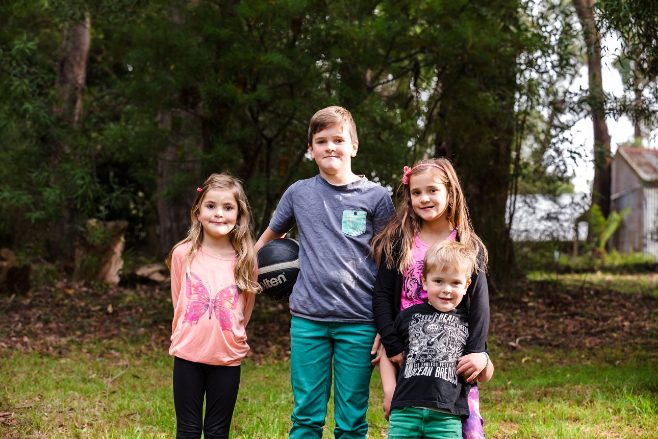 the kids at home on their parents land smiling for the family photographer during a session at home