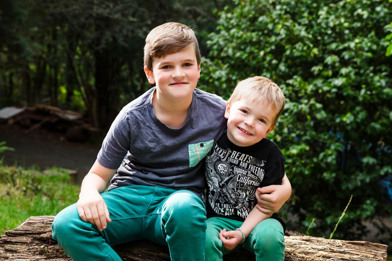 brothers sitting on a log at home during family portrait session at home